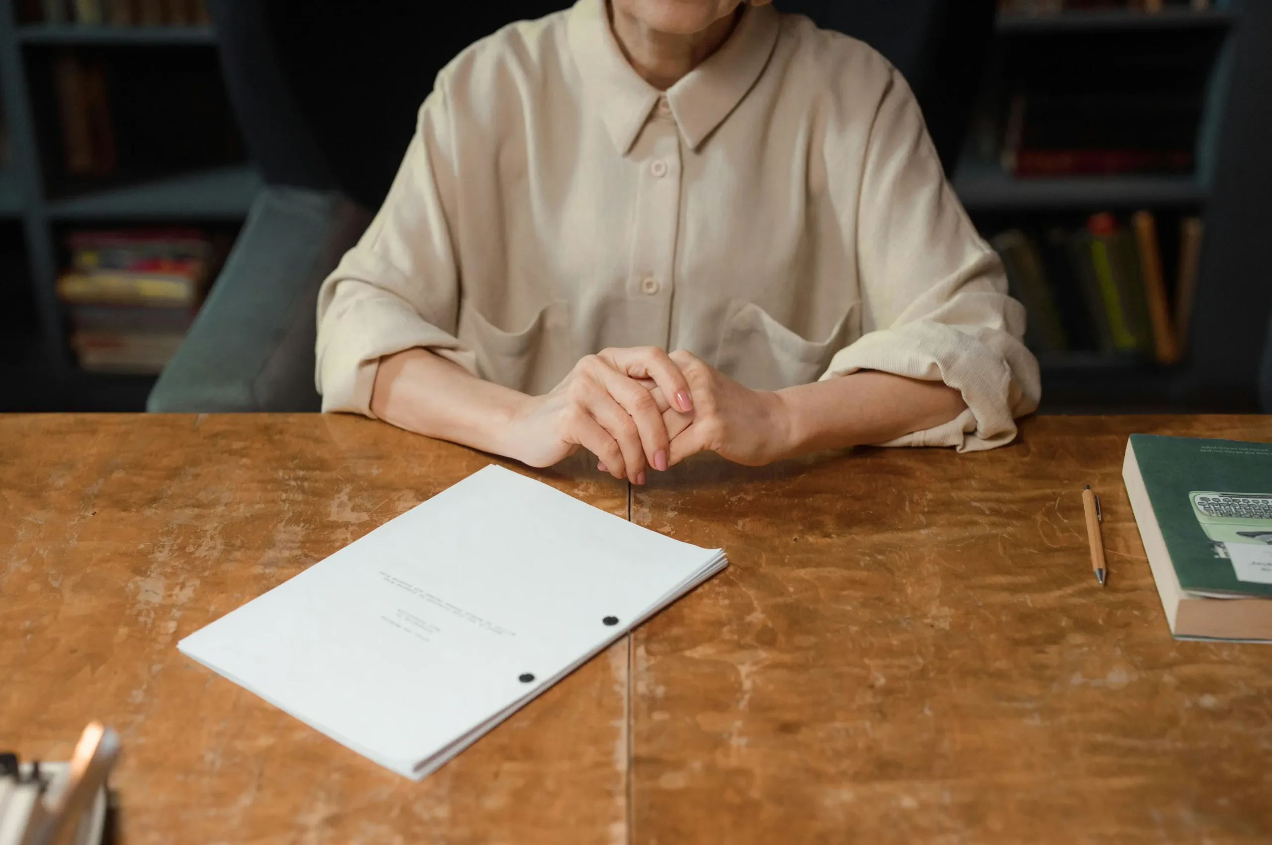 person with hands on desk and stack of papers