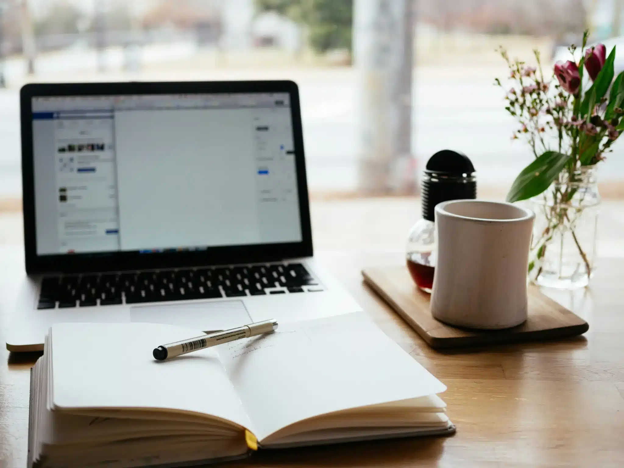 A Desk With a Laptop, Notebook, Pen and Mug