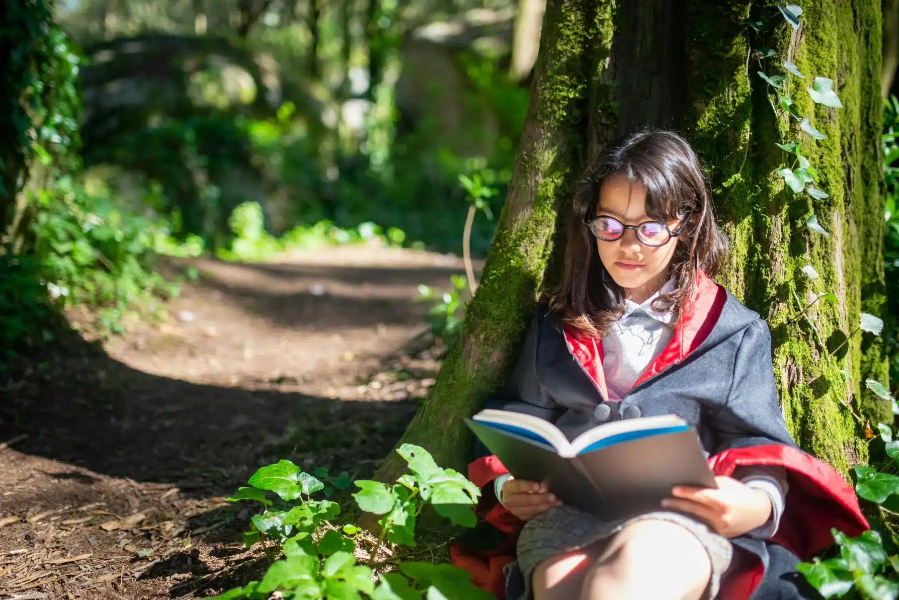 A Young Girl Reading a Book While Dressed Like Harry Potter