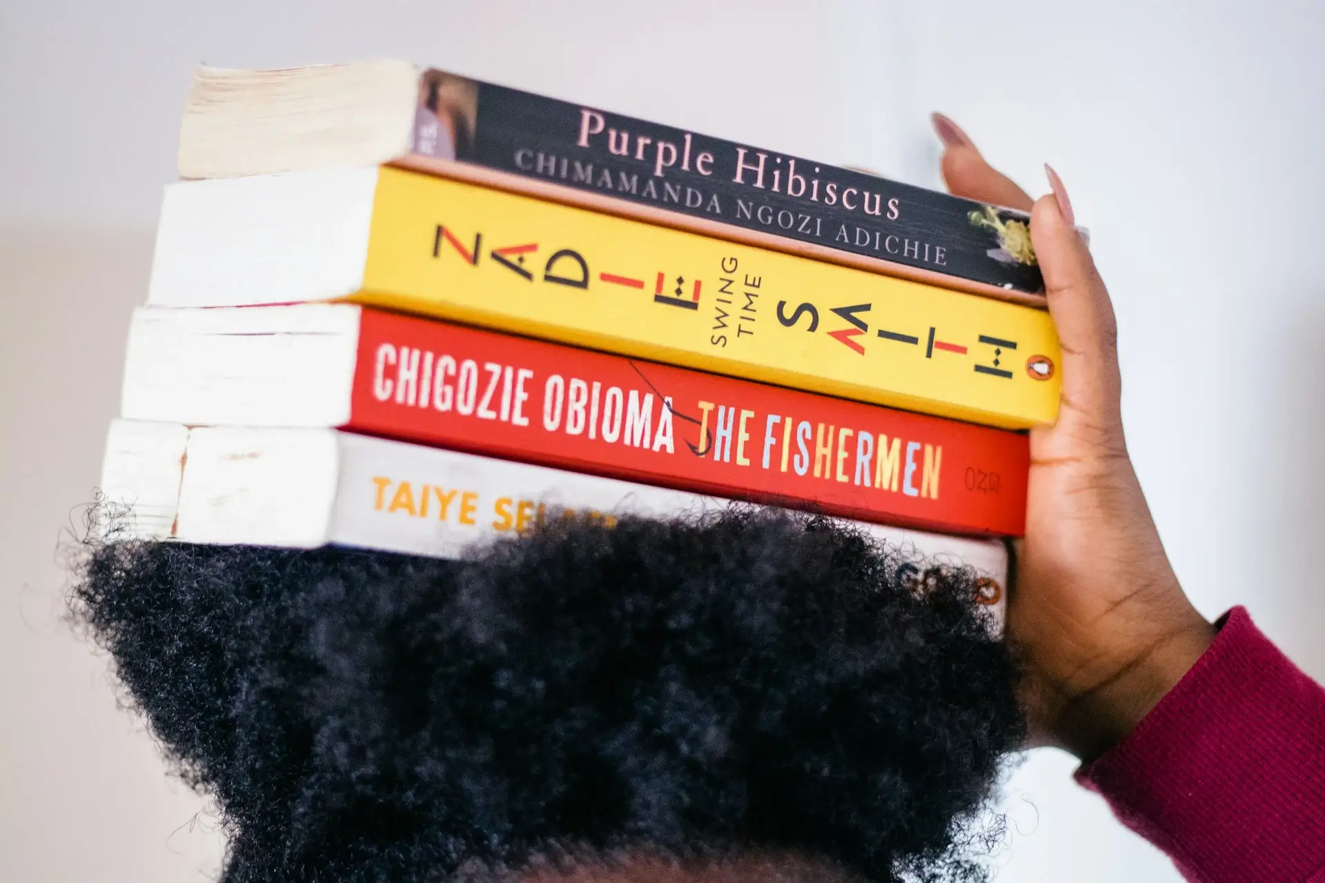 A Young Woman Holding a Stack of Literary Novels on her Head